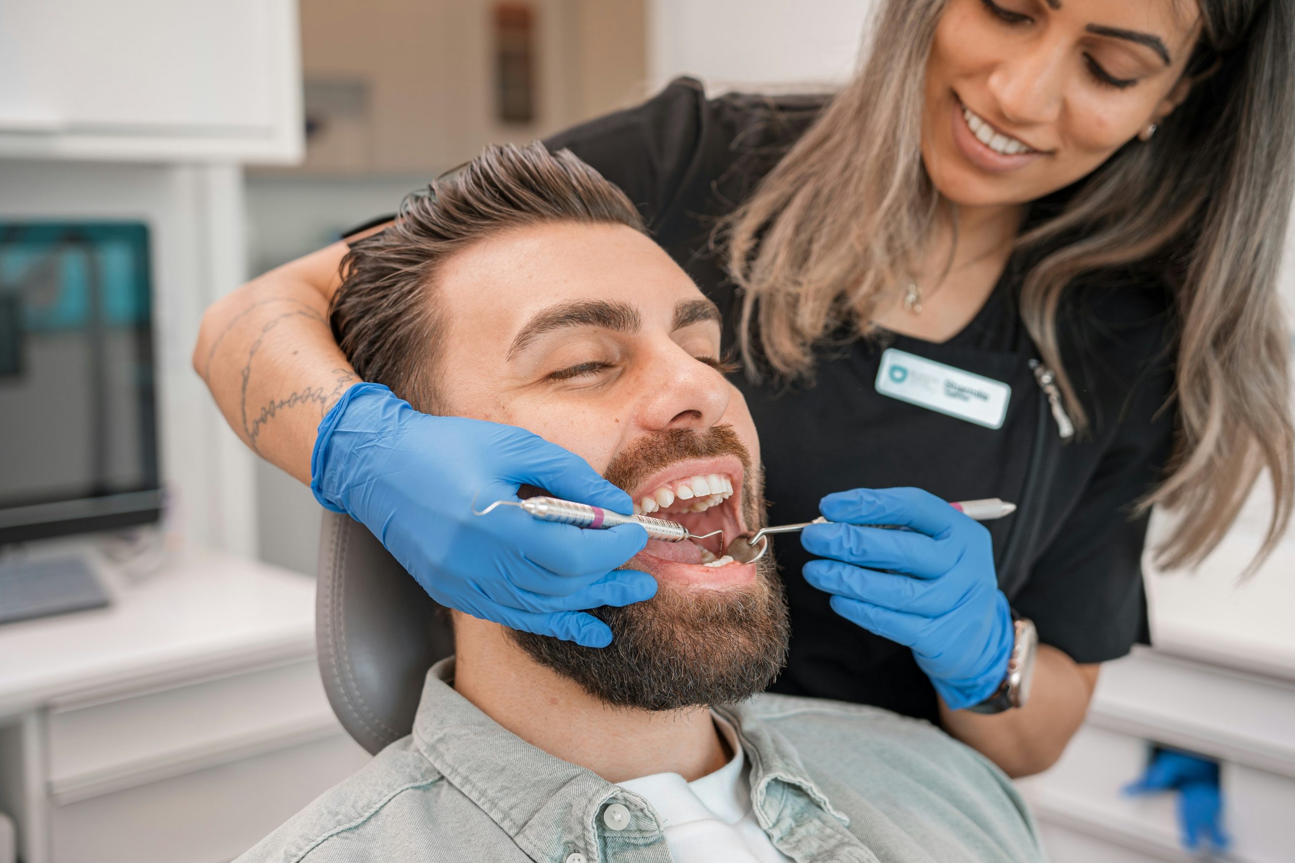 Dental hygienist cleaning a smiling patient's teeth